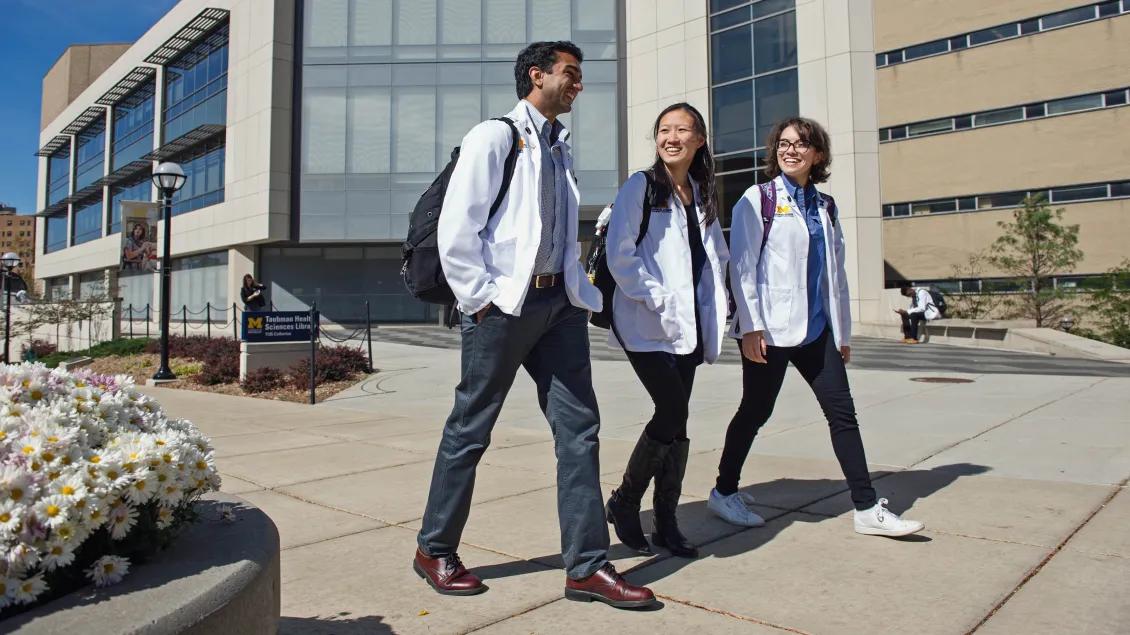 Medical students walking and talking by hospital in white coats