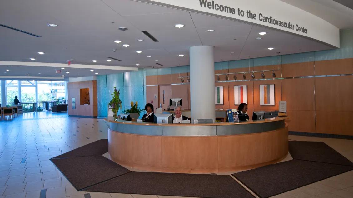 Three greeters sit at the large circular CVC welcome desk
