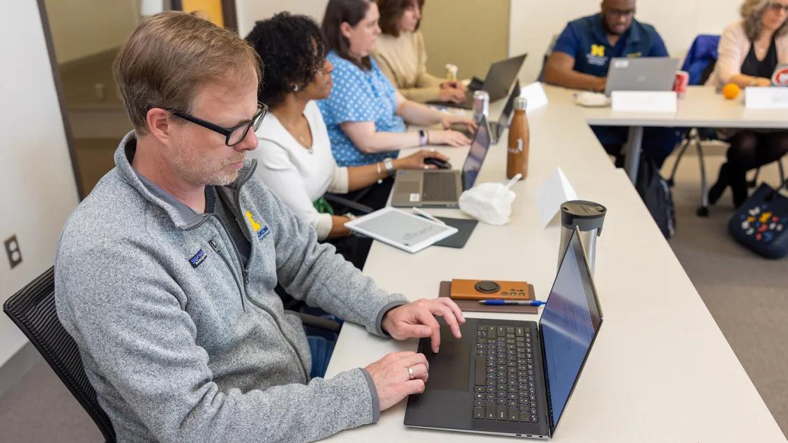 many people gathered around a table with laptops
