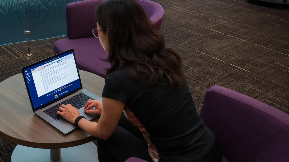 woman working on computer with Post Award Manual on the screen