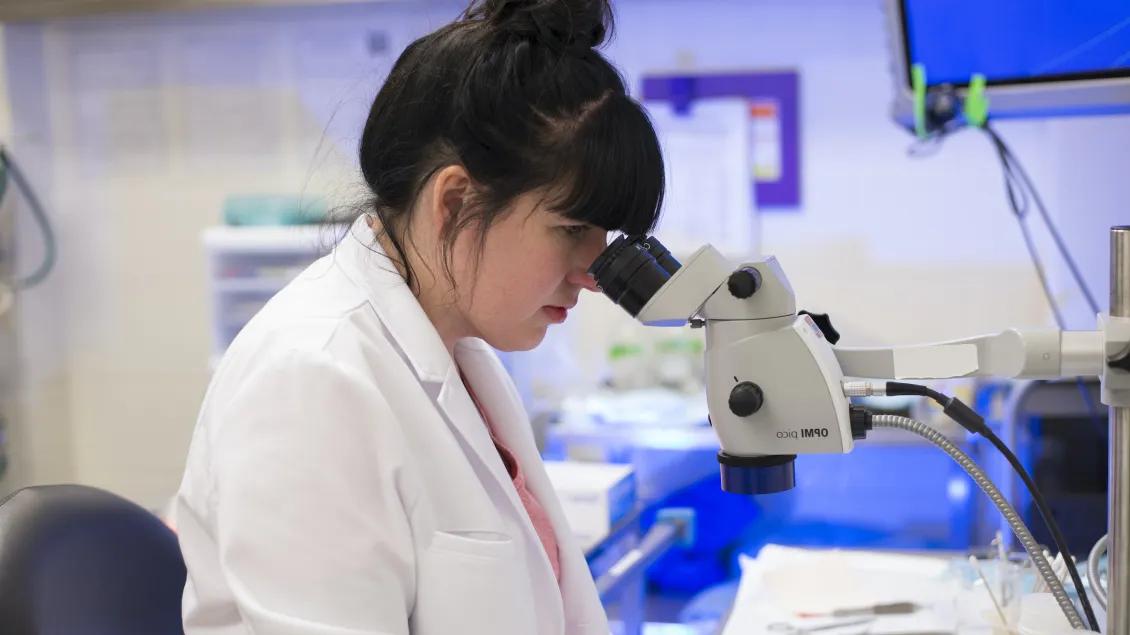 Woman with labcoat looking through a microscope