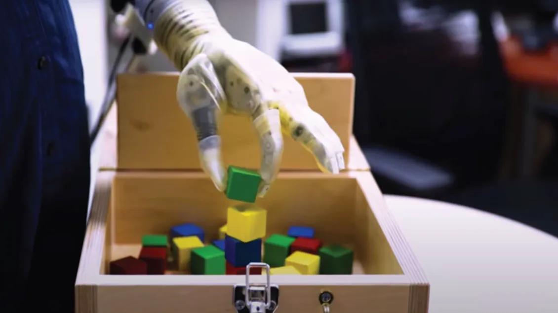Prosthetic hand places colorful blocks in a wooden box