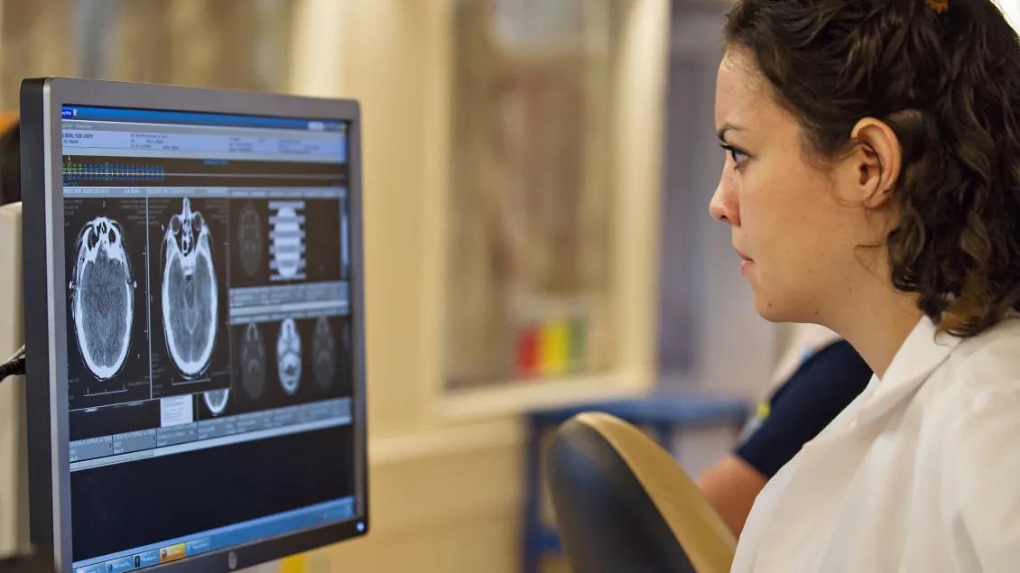 A woman in a lab coat looking at a computer screen
