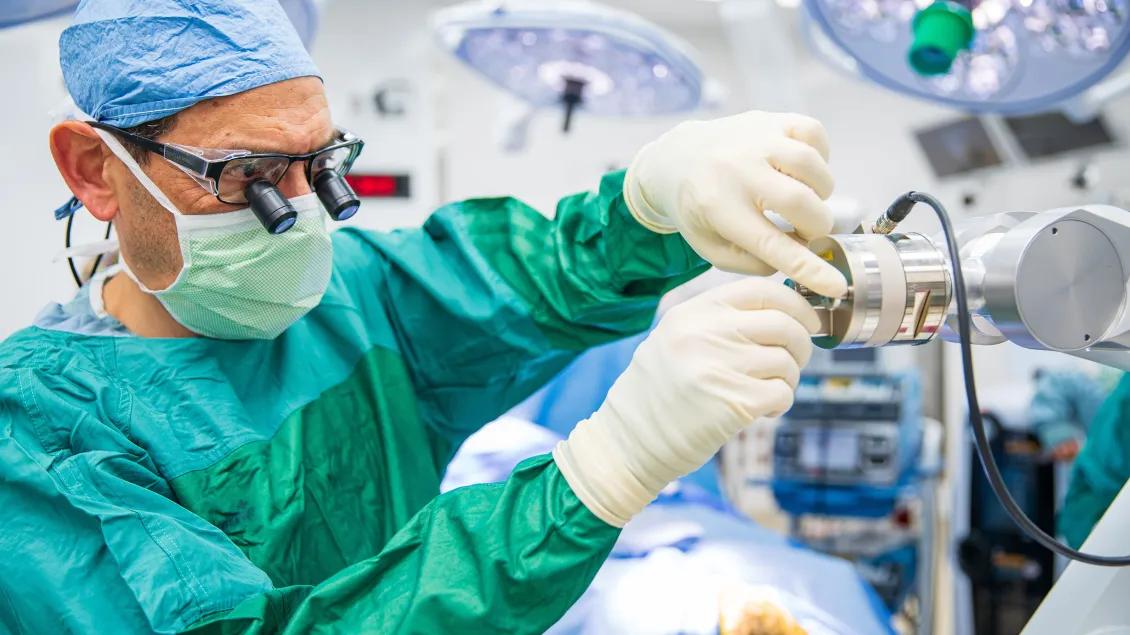  A surgeon working on a machine in an operating room. A surgeon working on a machine in an operating room
