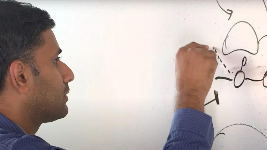 Researcher diagrams process on whiteboard