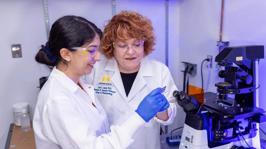 faculty in lab coats looking at microscopes