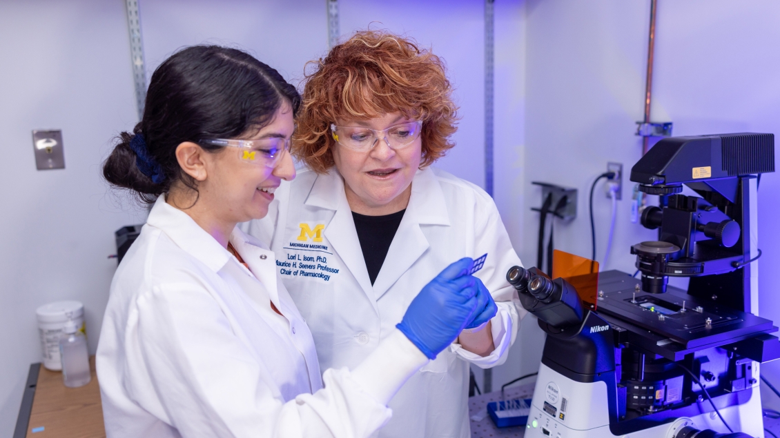 faculty in lab coats looking at microscopes