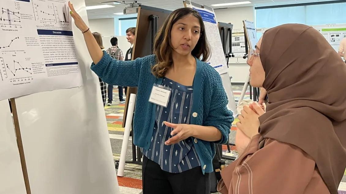 Pharmacology researchers discuss a poster and its data