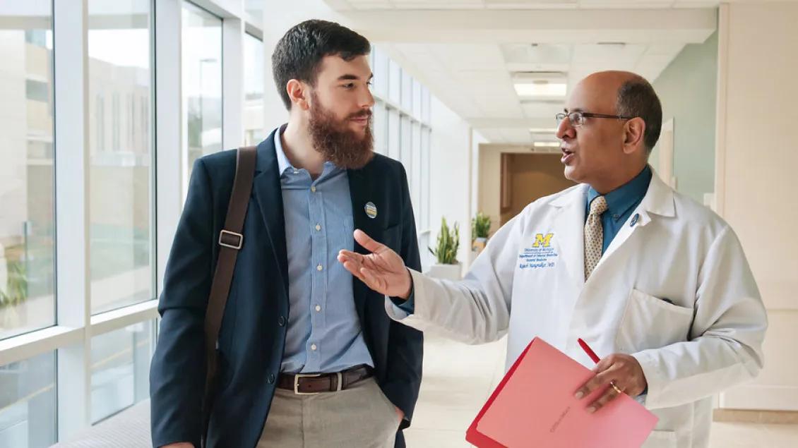 Physician talks with man in the hallway