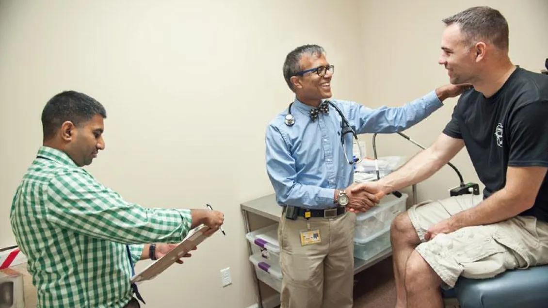 A provider shakes hands with a patient and smiles