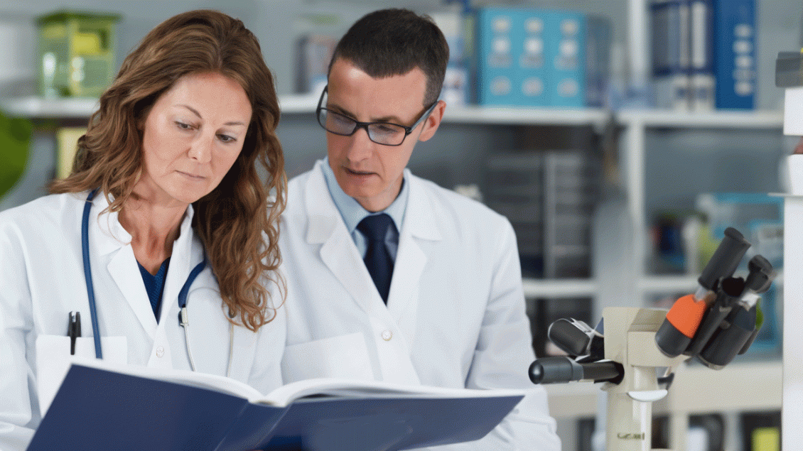 Two people with white coats reading a book