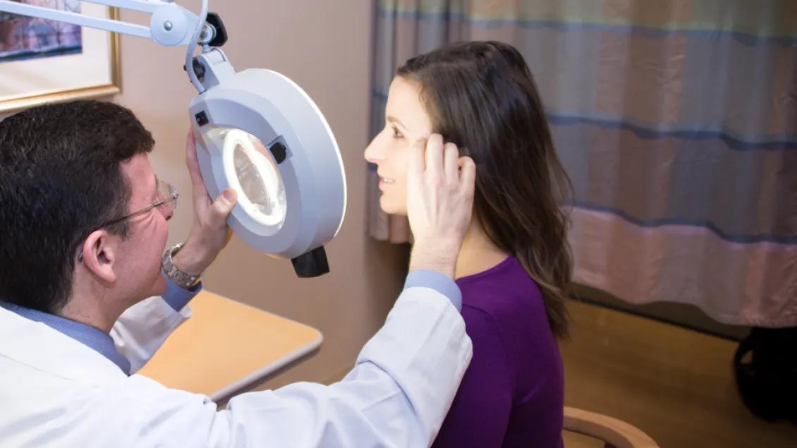 Dermatologist examines woman's face