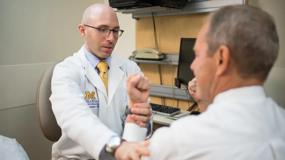 Stephen Gout an holding the wrist of a patient