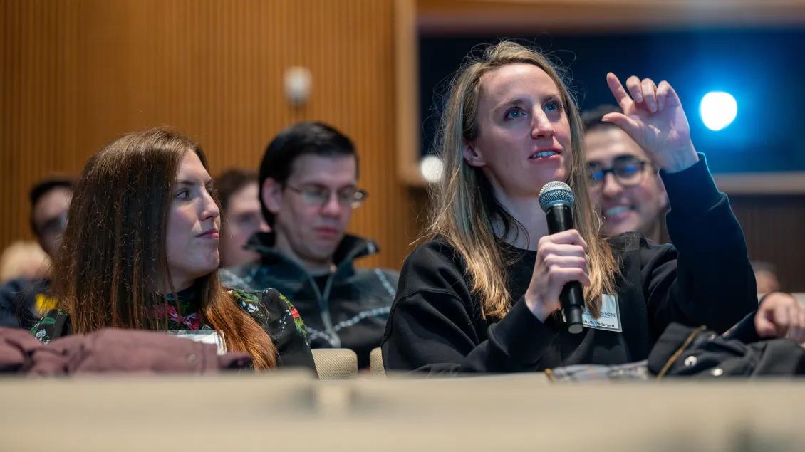 Woman speaking into microphone at a symposium