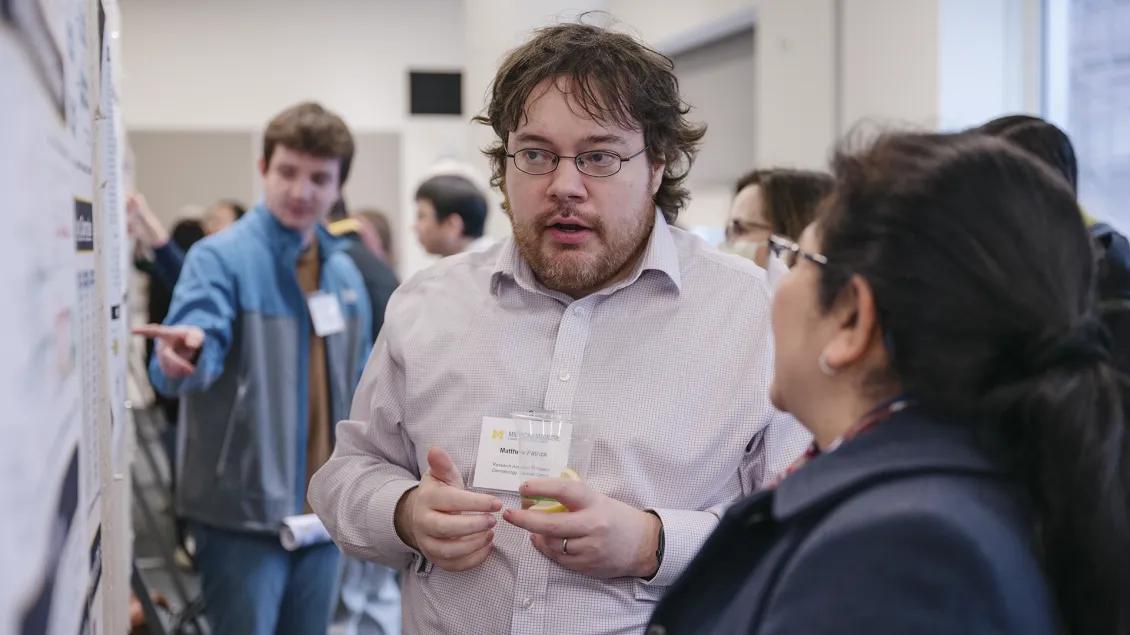 Scientist discussing his research poster with a colleague