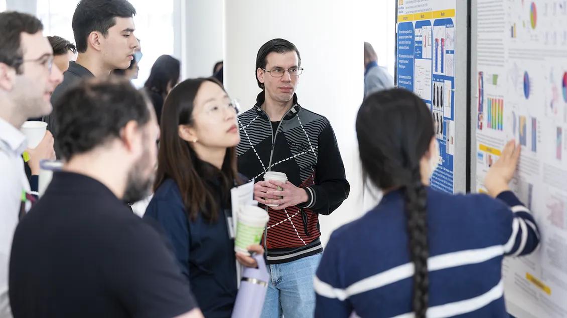 group of people discussing a scientific research poster