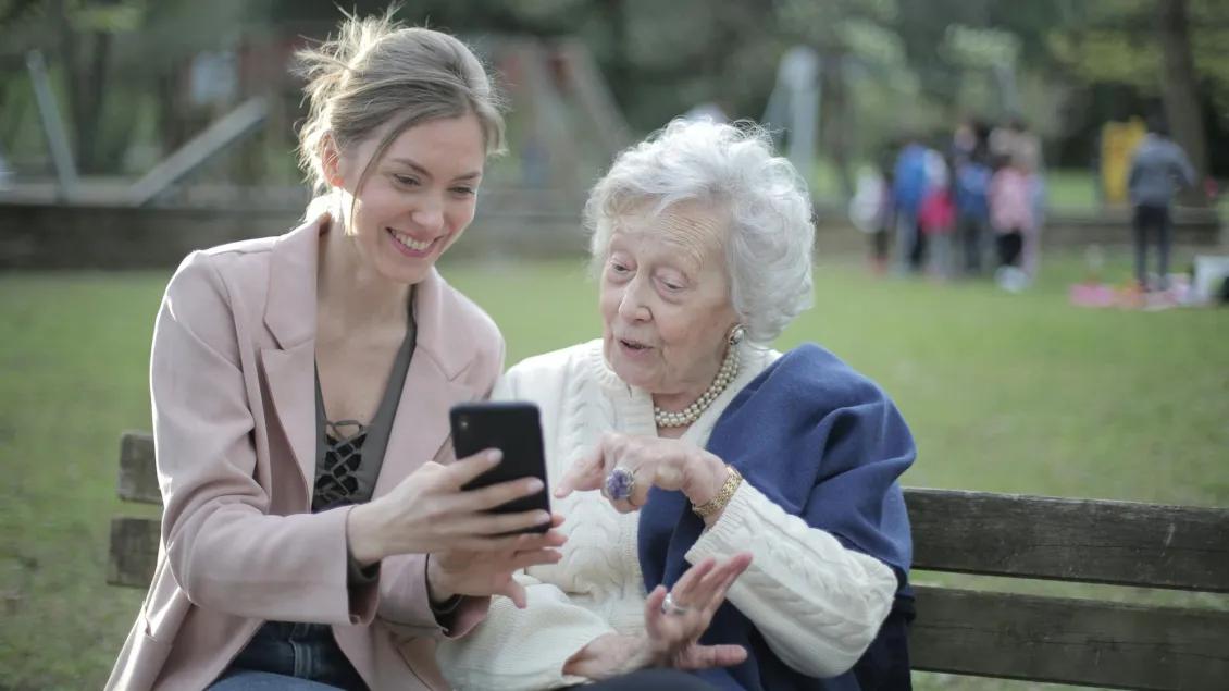 A young woman shows an elderly woman her iPhone
