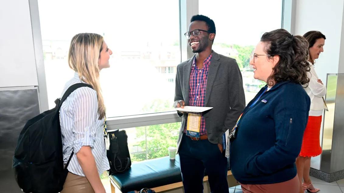 A diverse group of four people engage in a lively conversation by a window.