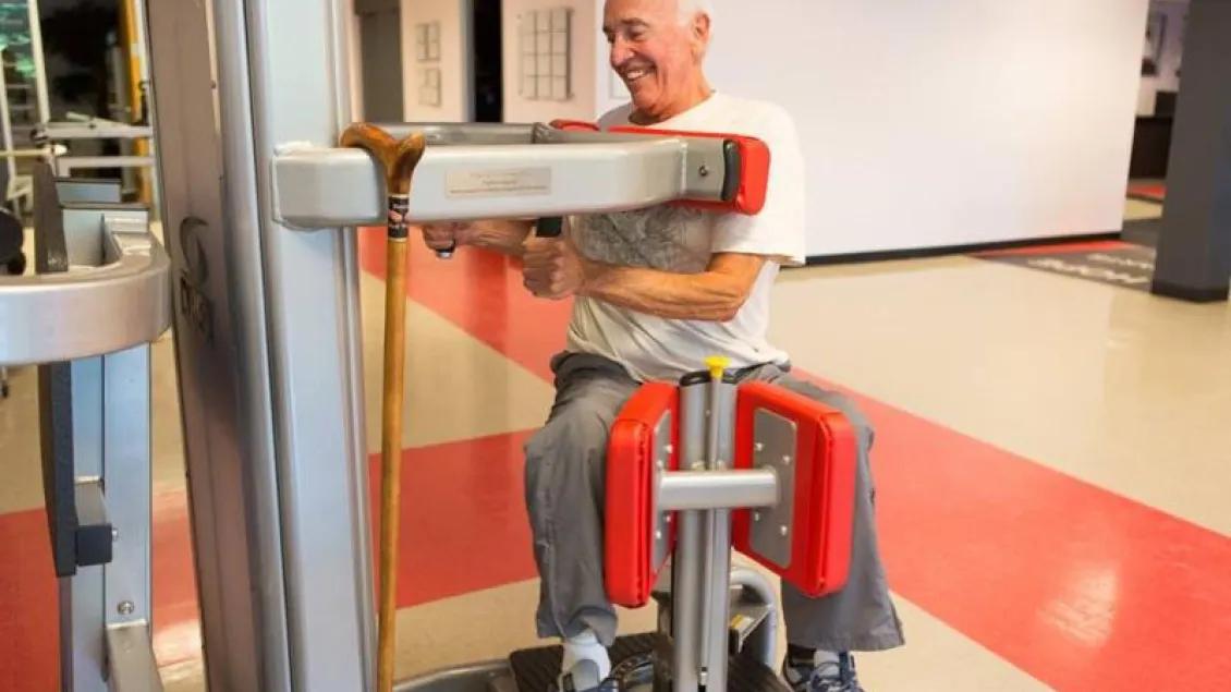 A man with Parkinson Disease using a leg weight machine