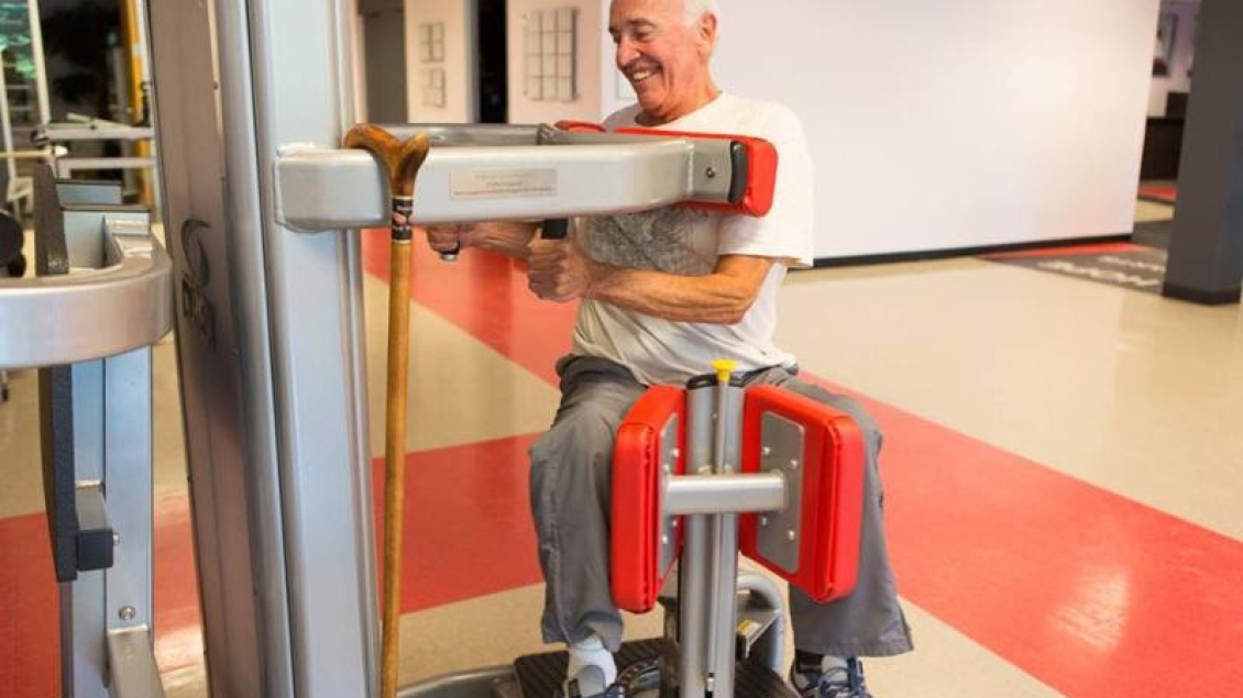 A man with Parkinson Disease using a leg weight machine