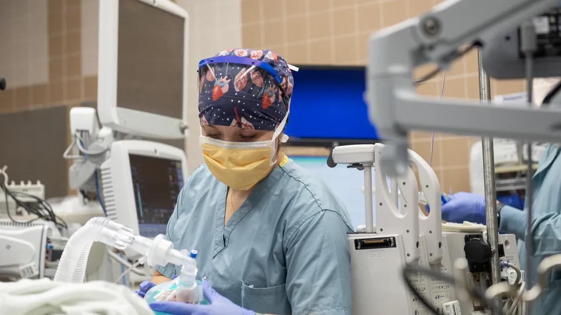a technician in the OR holds the medical equipment for the patient 