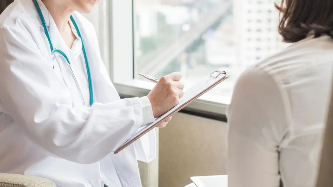 Researcher Writes On Clipboard With Person in Foreground