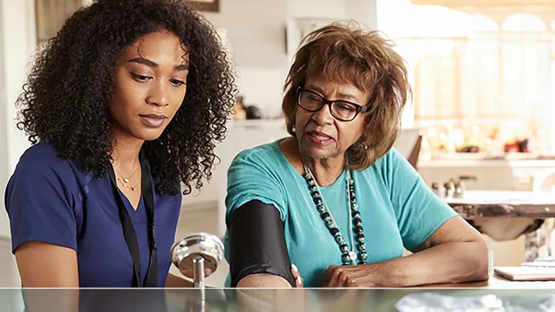 Healthcare professional reviews older woman's blood pressure