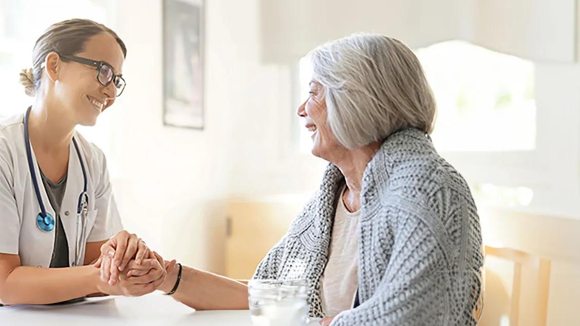 Doctor smiling at the patient holding hands.