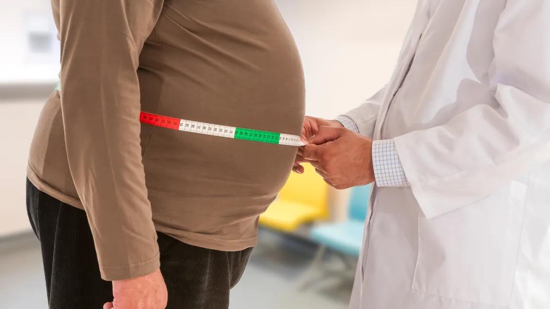 doctor measuring an obese man's waist