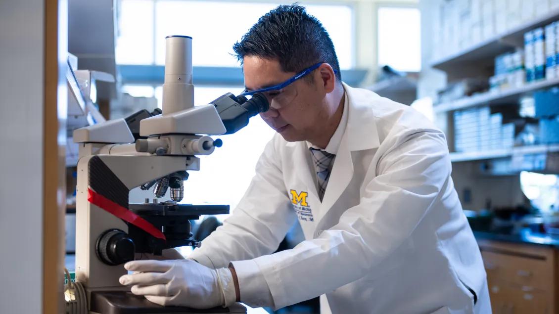 Neurosurgeon and neurologist Dr. Kevin Chen looking at a microscope