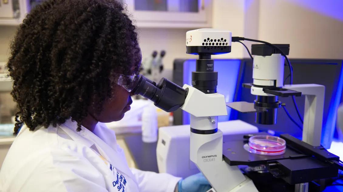 woman in laboratory looking through a microscope 