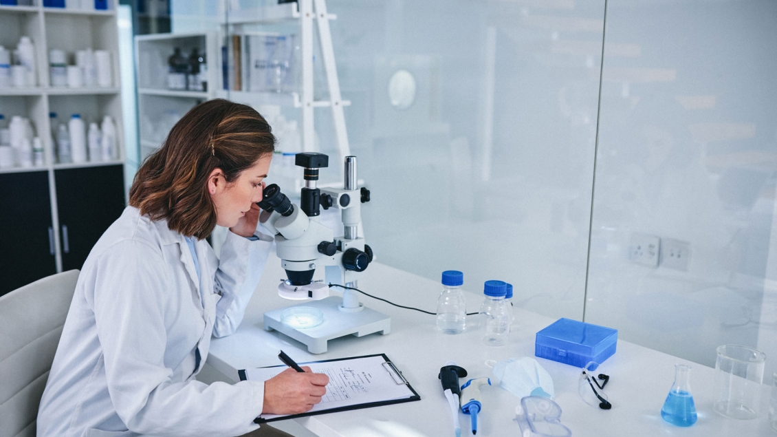 Researcher taking notes with microscope