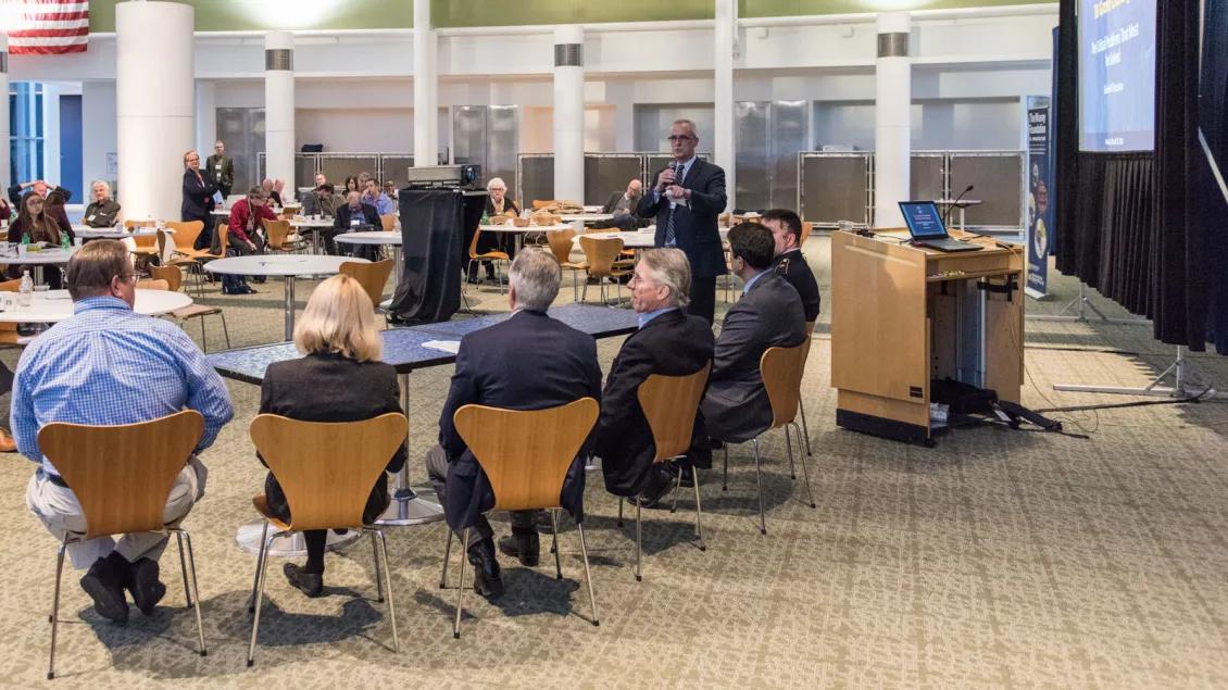 Moderator addresses six panel participants