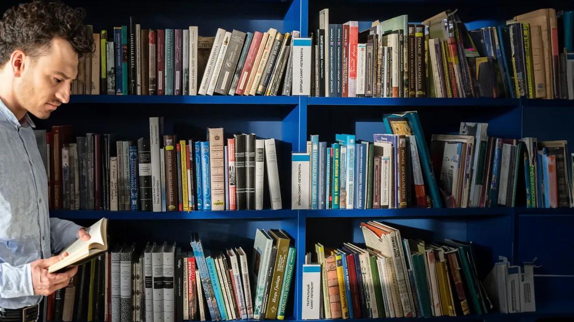 Man reading in front of shelves full of books