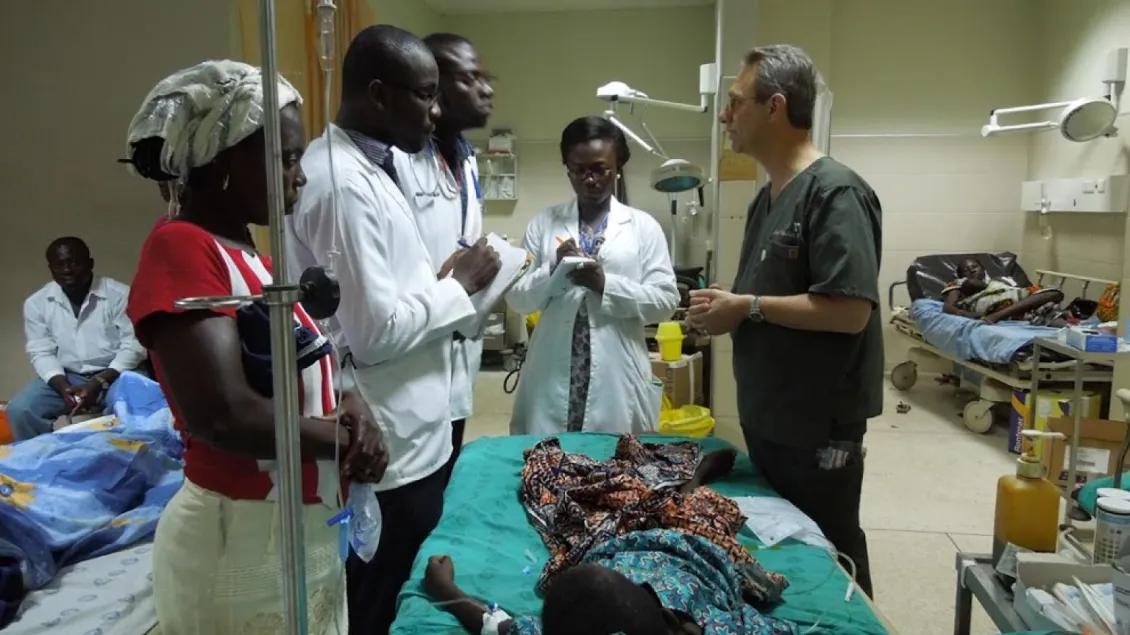 Medical professionals surrounding a child patient are taking notes. 