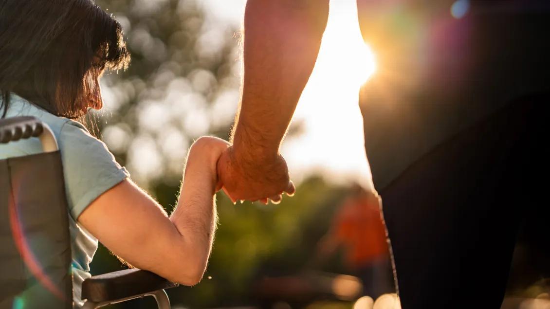 Dad holds hands with daughter in wheelchair