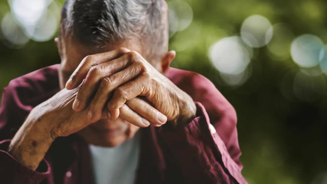 depressed or anxious man with his forehead resting on his hands