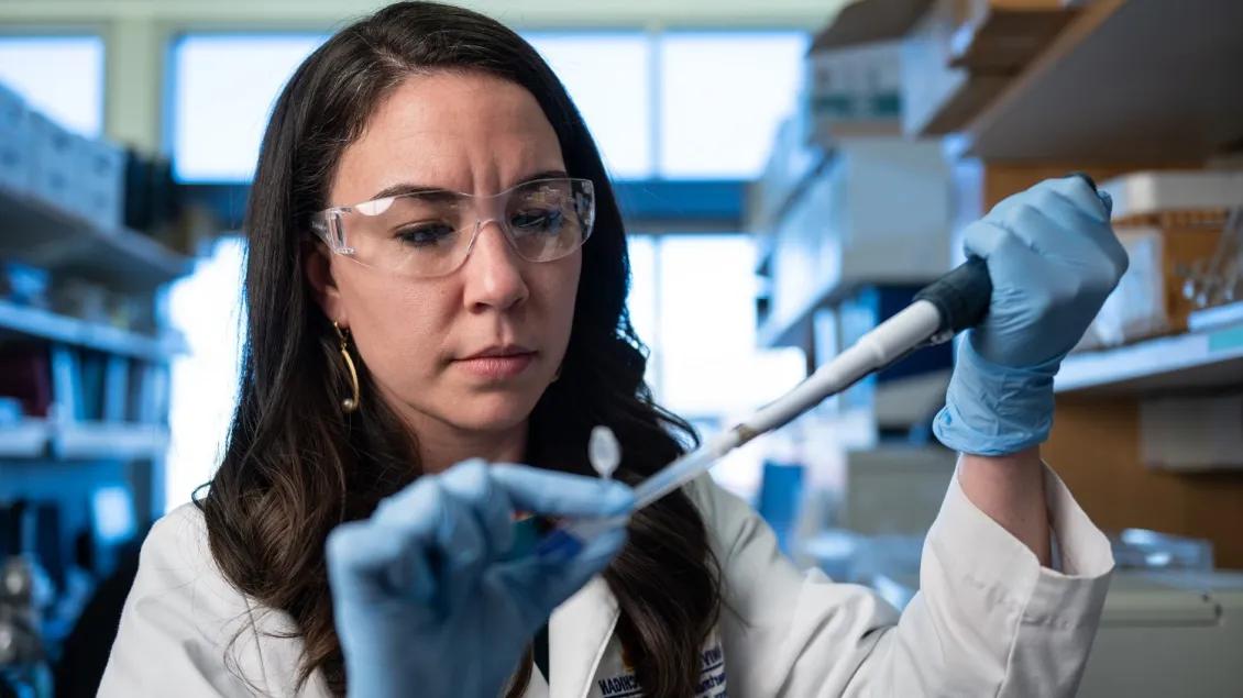Woman in laboratory using pipette and PPE