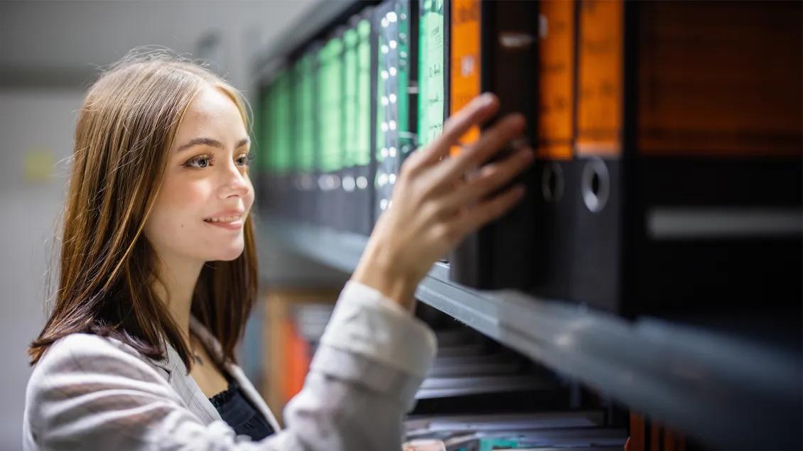 woman pulling large binder from a shelf