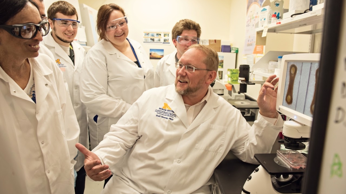 A group of researcher smiling and working in a lab.