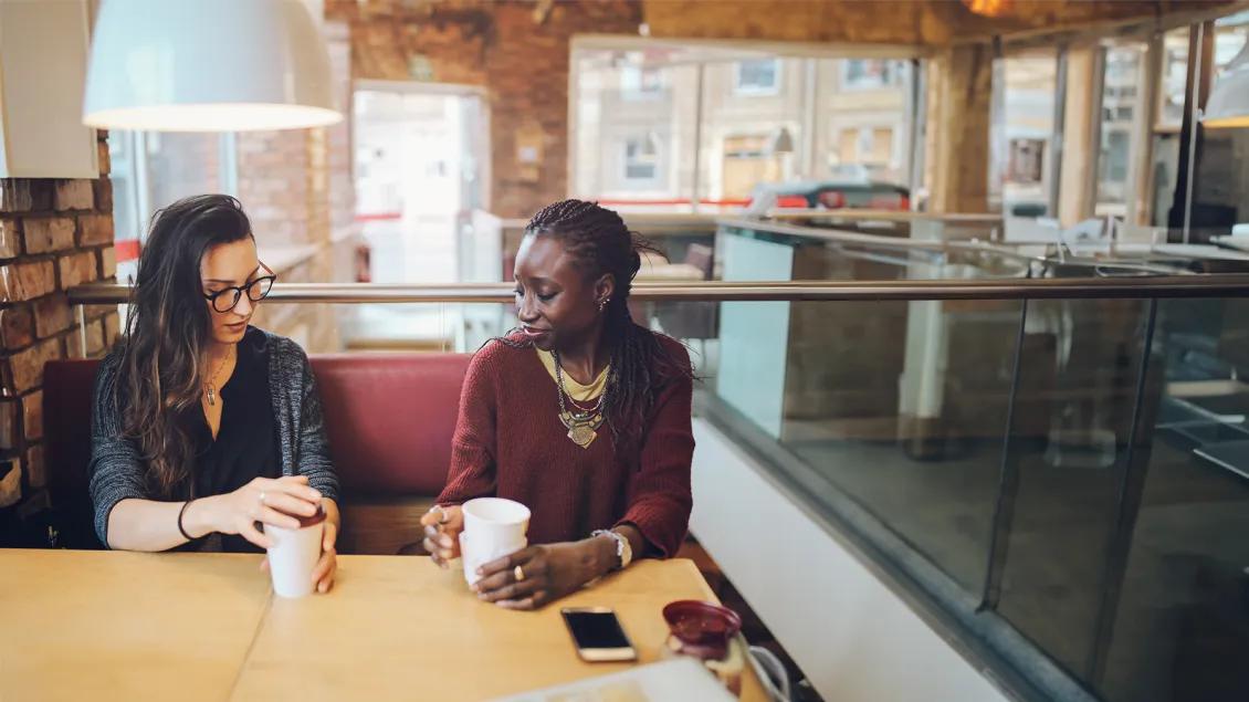 two woman talking and drinking coffee