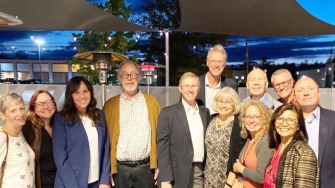 A group of colleagues posing together outdoors during an evening gathering.