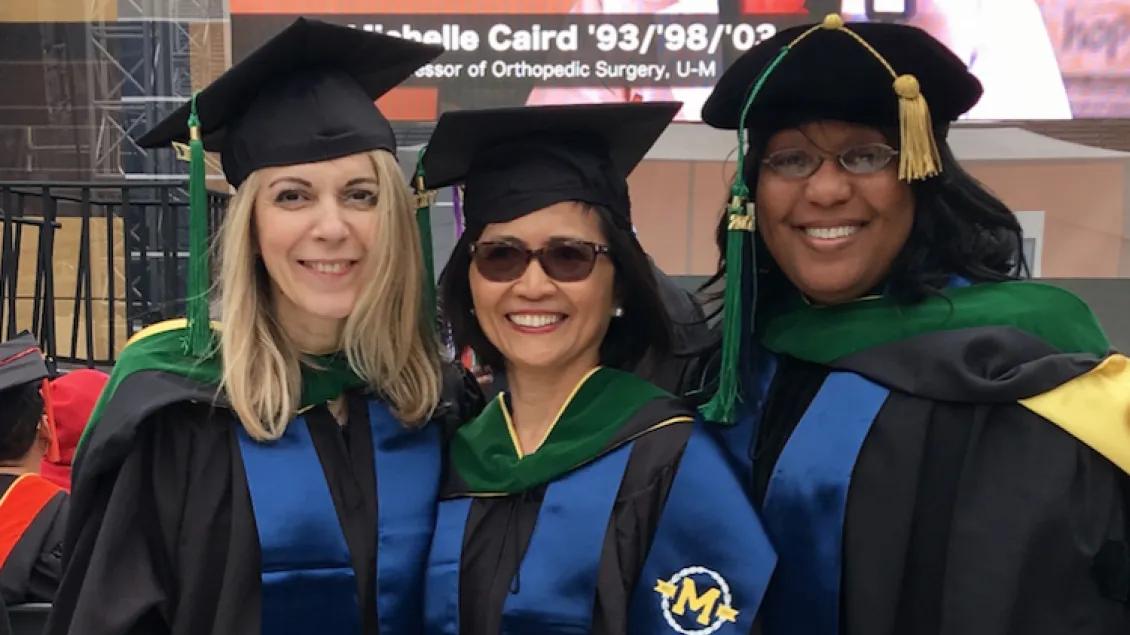 three graduates smiling at the camera