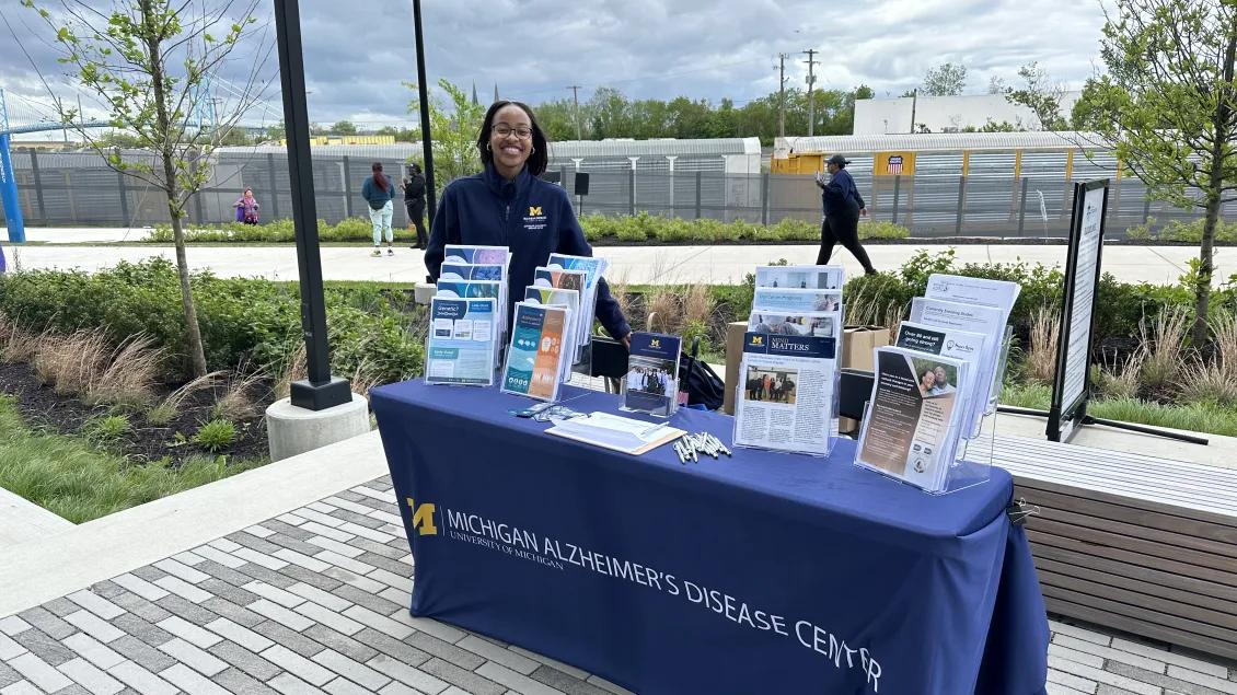 a woman wearing a blue sweatshirt standing behind a table with educational materials