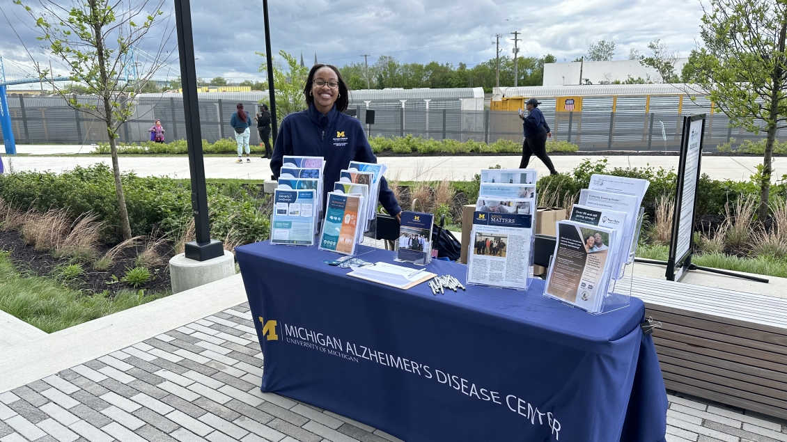 a woman wearing a blue sweatshirt standing behind a table with educational materials