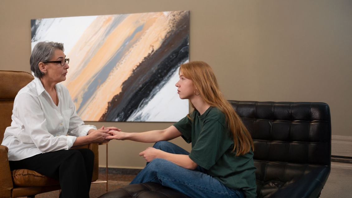 Therapist in a chair holding patients hand on a couch
