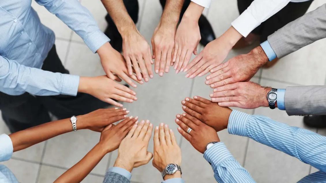 People with business shirts putting their hands in the center of a circle for a team cheer
