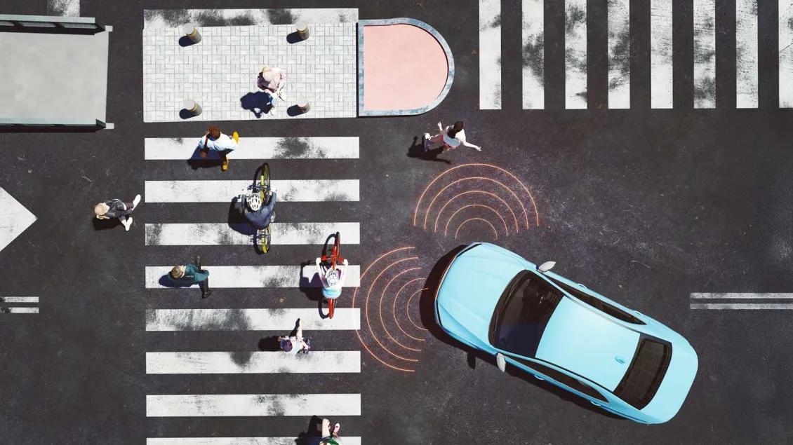 Overhead view of pedestrians on a cross walk with a car stopped in front.