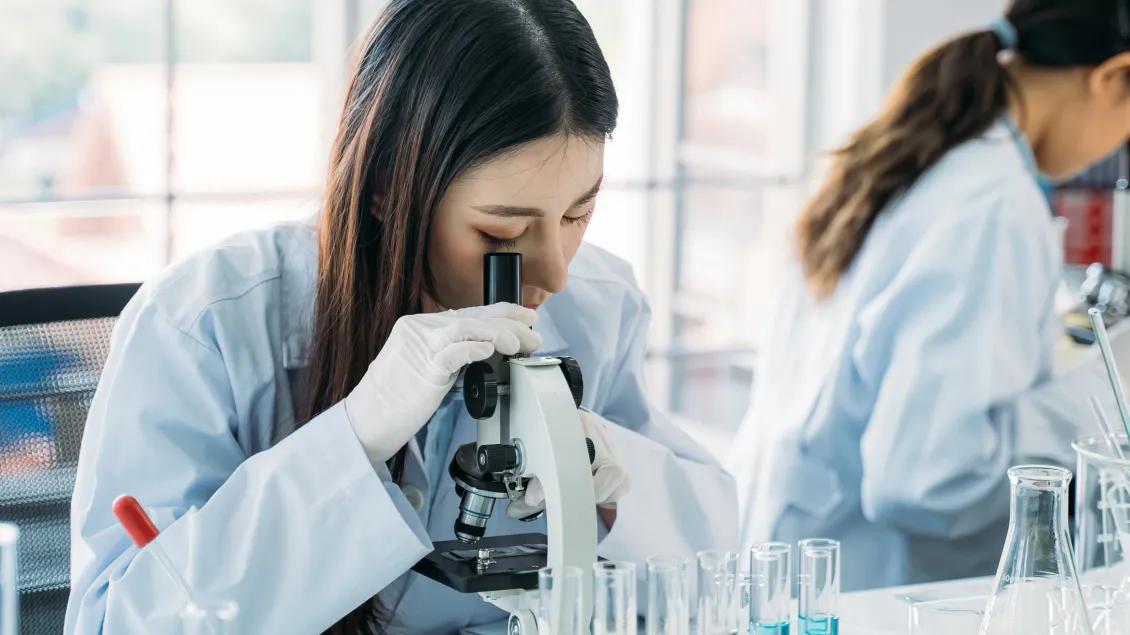 a woman looking into a microscope