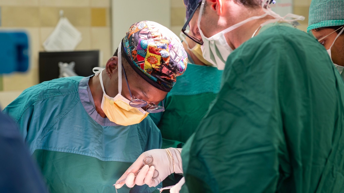 Pediatric surgeons using sutures in an operating room.